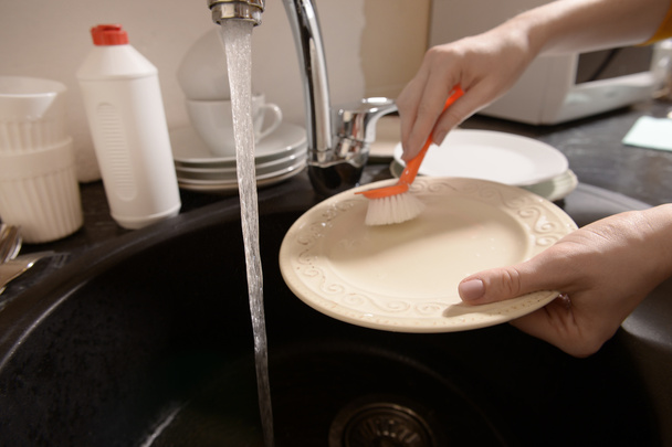 Женщина моет посуду в раковине
 - Фото, изображение