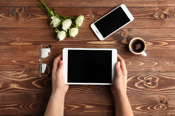 Mains féminines avec tablette PC, téléphone portable et tasse de café sur fond en bois
 - Photo, image
