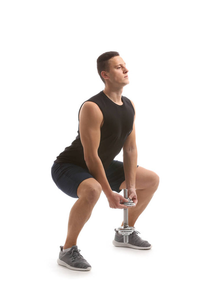 Sporty young man training with dumbbell against white background - Photo, Image