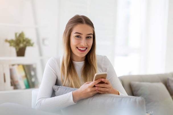 Young woman using her smartphone at home - Photo, Image