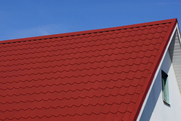 azulejo rojo en el techo del ático de un gran edificio privado con una ventana contra el cielo azul en la calle
 - Foto, Imagen