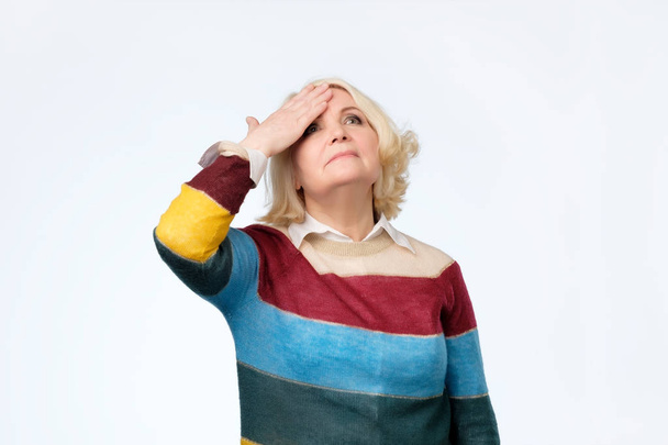 Senior blonde vrouw verrast met de hand op het hoofd voor fout, niet vergeten fout - Foto, afbeelding