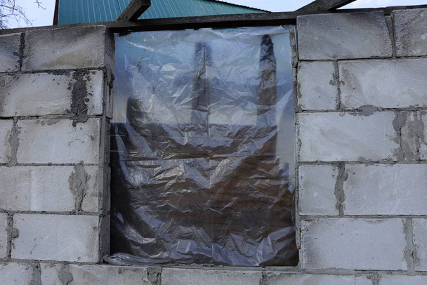 недостроенный дом из кирпича и окна, закрытые целлофаном
 - Фото, изображение