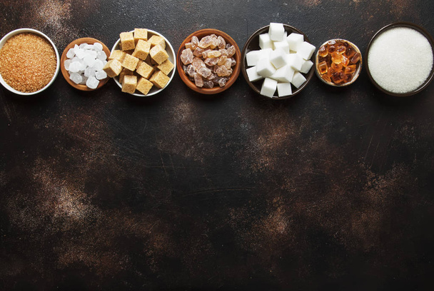 Set of different white and brown sugar in assortment, dark background, top view - Foto, immagini