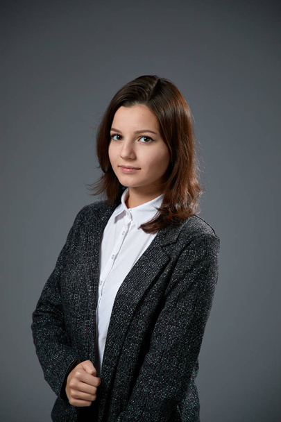 portrait of beautiful young woman wearing white shirt and black jacket posing on grey background   - Foto, Imagen
