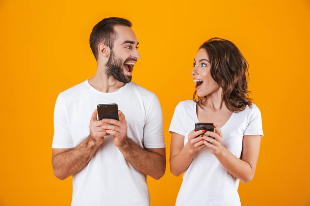 Image of excited couple man and woman smiling while both using m - Foto, Imagem