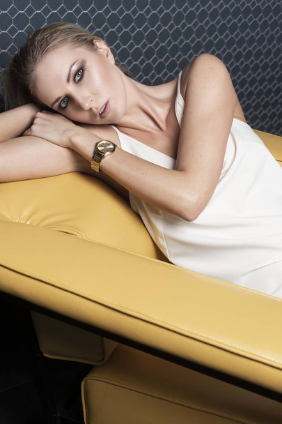 A beautiful blonde girl wearing a light white dress and a watche - Фото, зображення