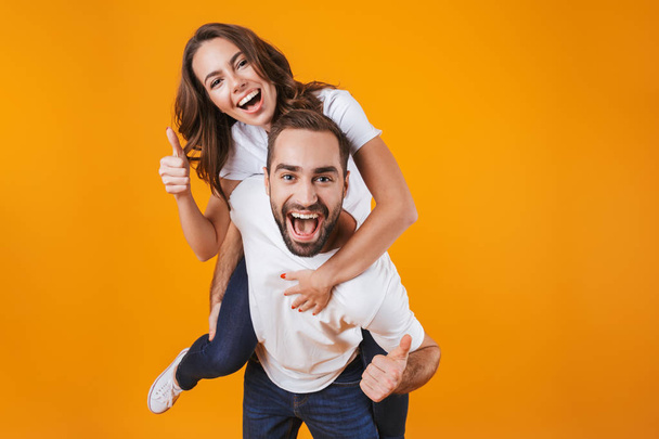 Image of smiling couple having fun while man piggybacking joyful - Фото, зображення