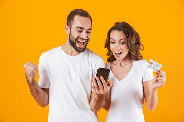 Image of kind couple man and woman using cell phone and credit c - Фото, зображення