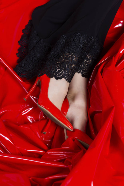 Beautiful female legs in red shoes and black dress with lace on  - Photo, image