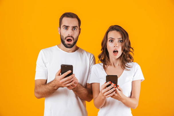 Image of shocked couple man and woman using smartphones together - Fotografie, Obrázek