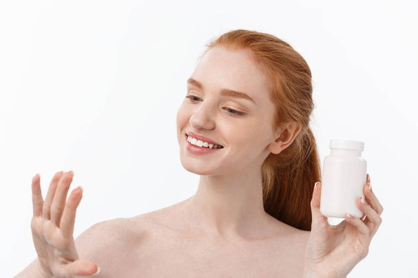 Portrait of good-looking young caucasian woman holding pills, trying to take care of immune system and health over gray background. - Photo, Image