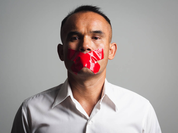 Man is silenced with adhesive red tape across his mouth sealed t - Photo, Image
