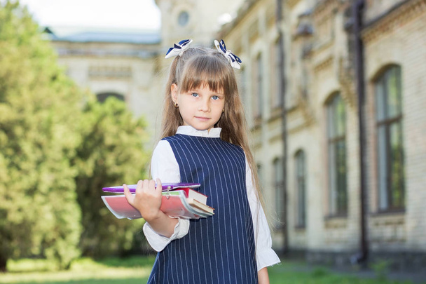 Terug naar school. Meisje schoolmeisje heeft boeken, notebooks en potlood in haar handen. - Foto, afbeelding