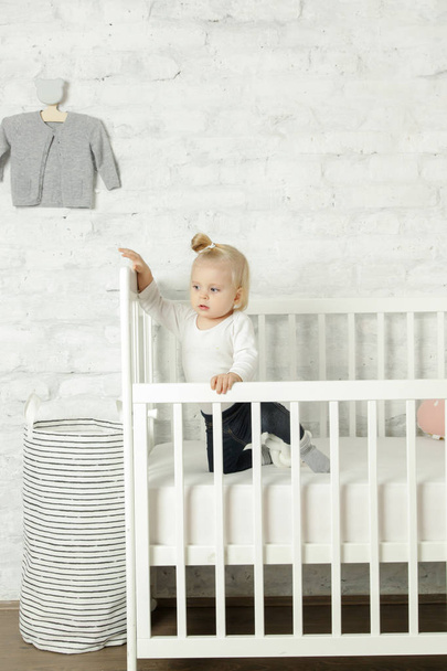 Adorable cheerful baby girl in the crib in the nursery room - Fotoğraf, Görsel