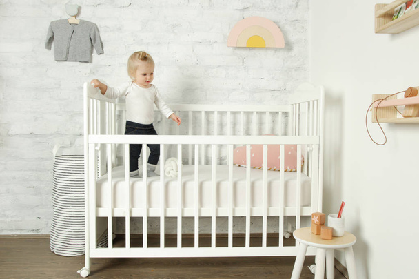 Adorable cheerful baby girl in the crib in the nursery room - Fotoğraf, Görsel