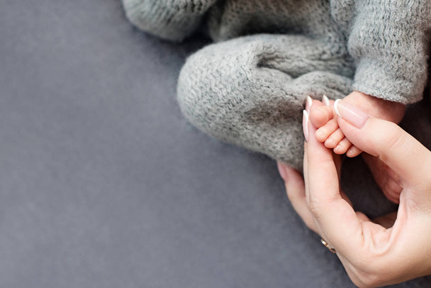 Voeten van een pasgeboren baby, tenen in de handen van moeder, handen en nagels van een kind, de eerste dagen van het leven na de geboorte, schilferige huid - Foto, afbeelding