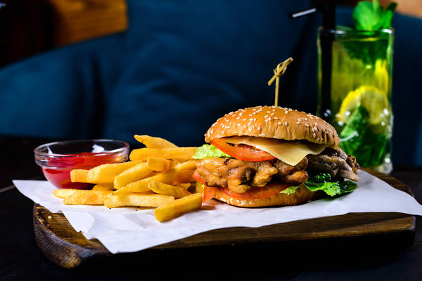 grilled chicken and french fries burger on a black table in a bar - Photo, image