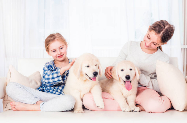 Sorelline sorridenti sedute con i cuccioli - Foto, immagini