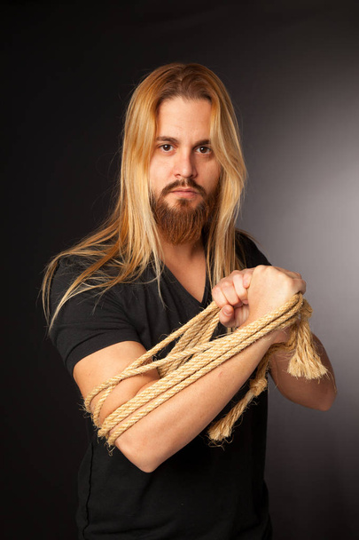 young boy with long hair and beard with rope on his arm - Foto, Imagen