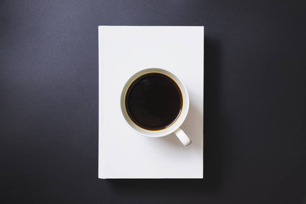 Черный кофе в белой кофейной кружке помещен на белые книги
 - Фото, изображение