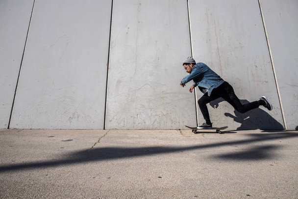 чоловічий скейтбординг біля стіни в міському місці
 - Фото, зображення
