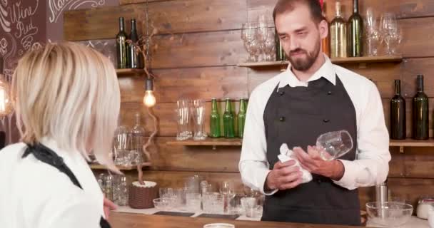 Knappe jonge bebaarde barman luistert naar de serveerster aan de bar - Video