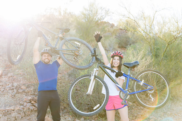 自分の自転車を持ち上げると勝利を楽しんで興奮しての若いカップルの肖像画 - 写真・画像