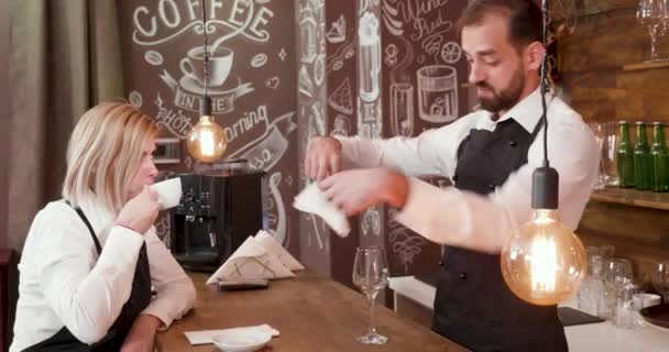 Красивий бармен в чорному фартусі розмовляє з офіціанткою
 - Кадри, відео