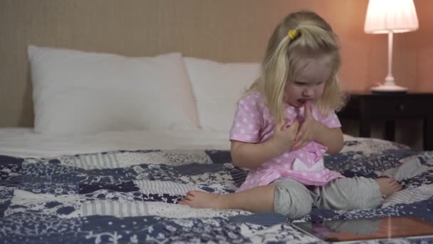 Little child girl with tablet computer on bed. - Záběry, video