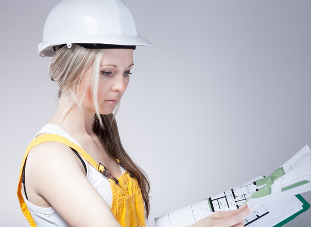 Young architect woman construction worker reading blueprints - Fotó, kép