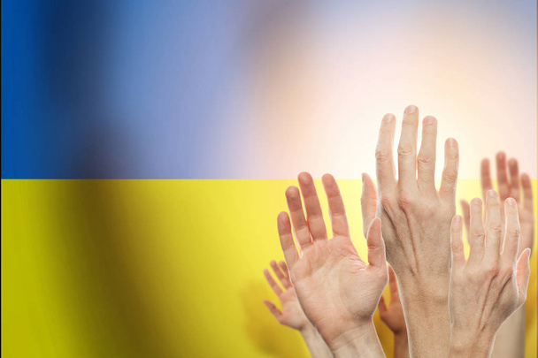 Pessoas levantando as mãos e bandeira Ucrânia em segundo plano
. - Foto, Imagem
