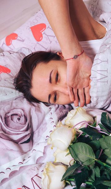 A bouquet of roses on the bed of a sleeping young girl - Photo, Image