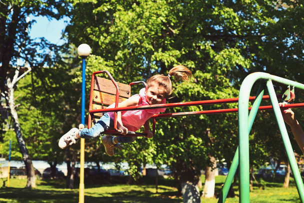 childhood daydream .teen freedom. Small kid playing in summer. Playground in park. Happy laughing child girl on swing. romantic little girl on the swing, sweet dreams. I am free - Фото, зображення