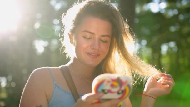 Pretty european woman in dress makes selfie and texts with her mobile phone in forest on sunset, selfie outdoors, using mobile phone in summer forest - Кадры, видео