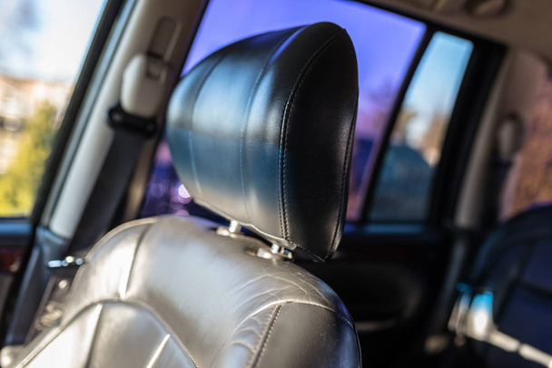 Leather car headrest illuminated by the sun, inside the used car, visible signs of use. - Φωτογραφία, εικόνα