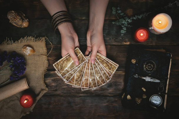 Tarot cards, magic book and fortune teller hands on a wooden table background. Future reading concept. Divination. - Fotografie, Obrázek