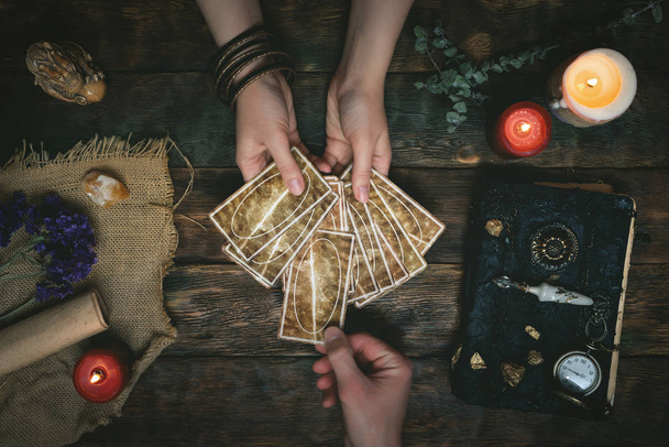 Tarot cards, magic book and fortune teller hands on a wooden table background. Future reading concept. Divination. - 写真・画像