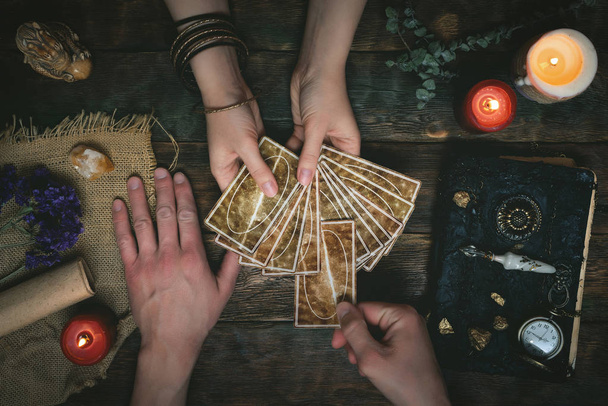 Tarot cards, magic book and fortune teller hands on a wooden table background. Future reading concept. Divination. - Фото, изображение