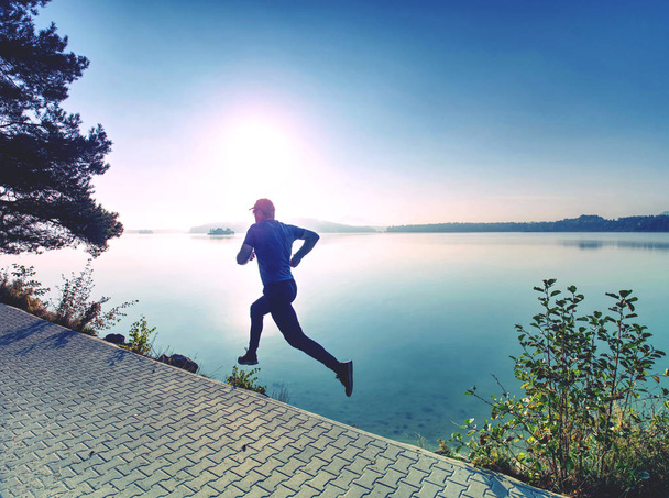 Tavallinen juoksu järvellä. Mies juoksija sprinting ulkona luonnonkauniissa luonnossa
 - Valokuva, kuva
