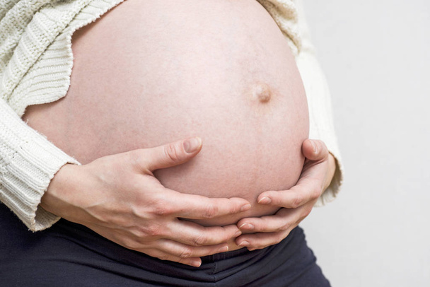 Schwangerschaft, Mutterschaft, Menschen und Erwartungskonzept - Nahaufnahme einer glücklichen Schwangeren mit dickem Bauch - Foto, Bild