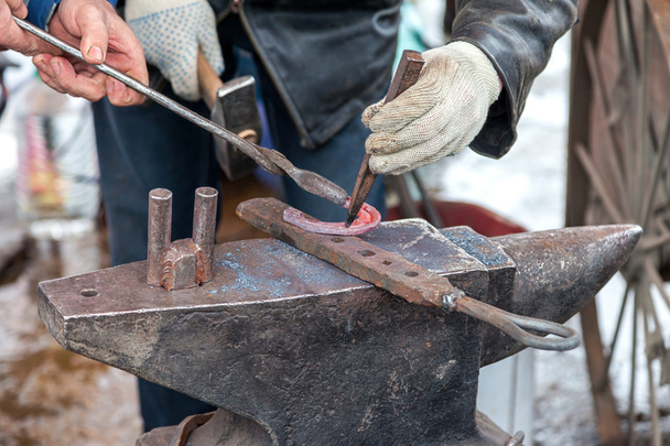 Blacksmith forges a hot horseshoe on the anvil - Photo, Image