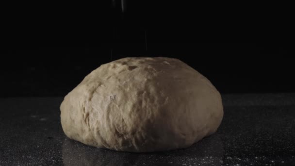 Close-up of sprinkling flour dough, black background. Frame. Sprinkle flour on dough on dark background - Footage, Video