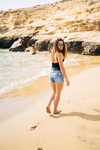 Pretty young woman walking on the beach during summer holiday - Foto, Imagem