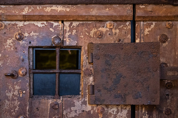 Ржавое стальное окно на очень старой деревянной двери в тюрьме
 - Фото, изображение