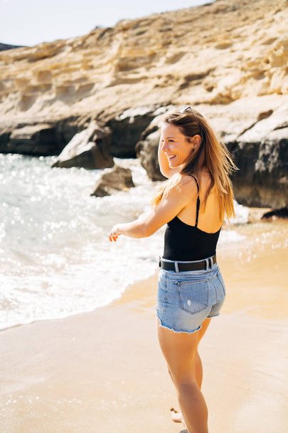 Pretty young woman walking on the beach during summer holiday - Фото, зображення