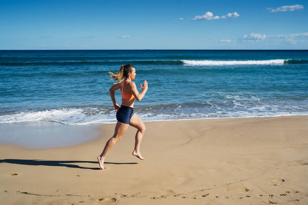 Fitness joven corriendo en la playa durante las vacaciones de verano
 - Foto, imagen