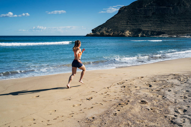 Fitness giovane donna che corre sulla spiaggia durante le vacanze estive
 - Foto, immagini