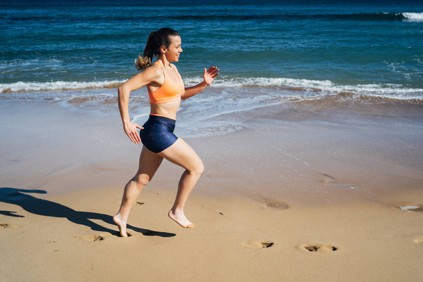 夏休みにビーチで走るフィットネスの若い女性 - 写真・画像