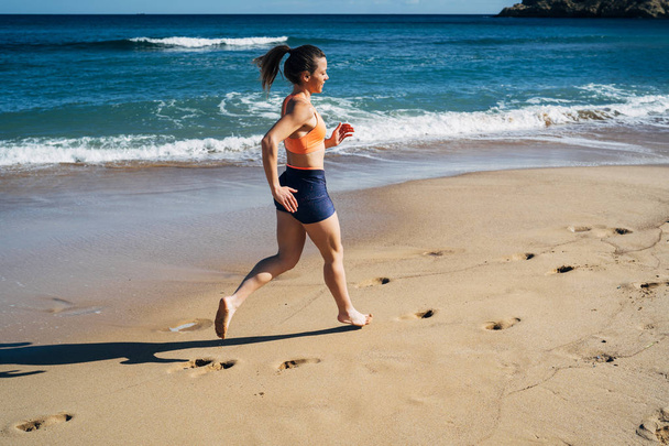 Fitness young woman running on the beach during summer holiday - Fotoğraf, Görsel